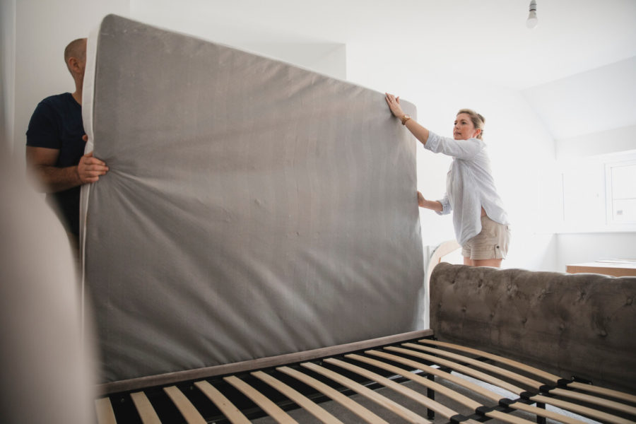Man and woman taking mattress off of bed frame